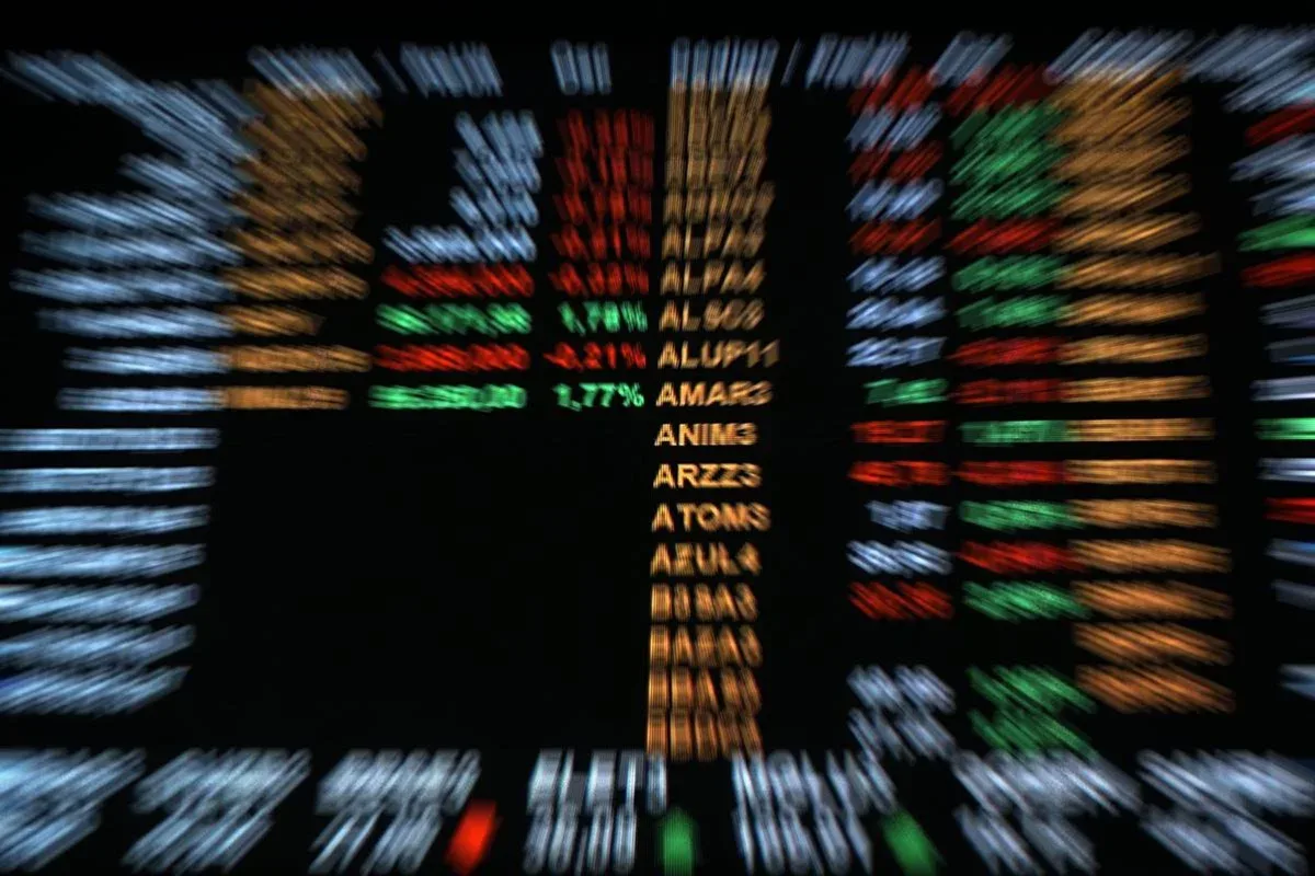 Painel digital exibindo números da Bolsa de Valores do Brasil em fundo desfocado.
