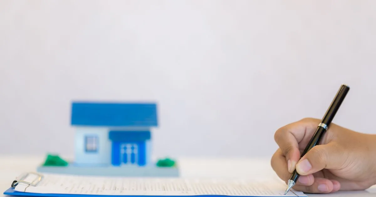 Pessoas assinando documentos de contrato imobiliário em uma mesa.