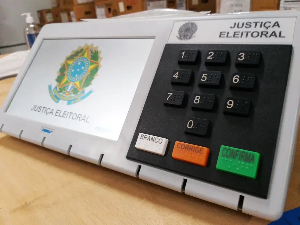 Técnicos manuseando urnas eletrônicas em depósito do TRE-CE.
