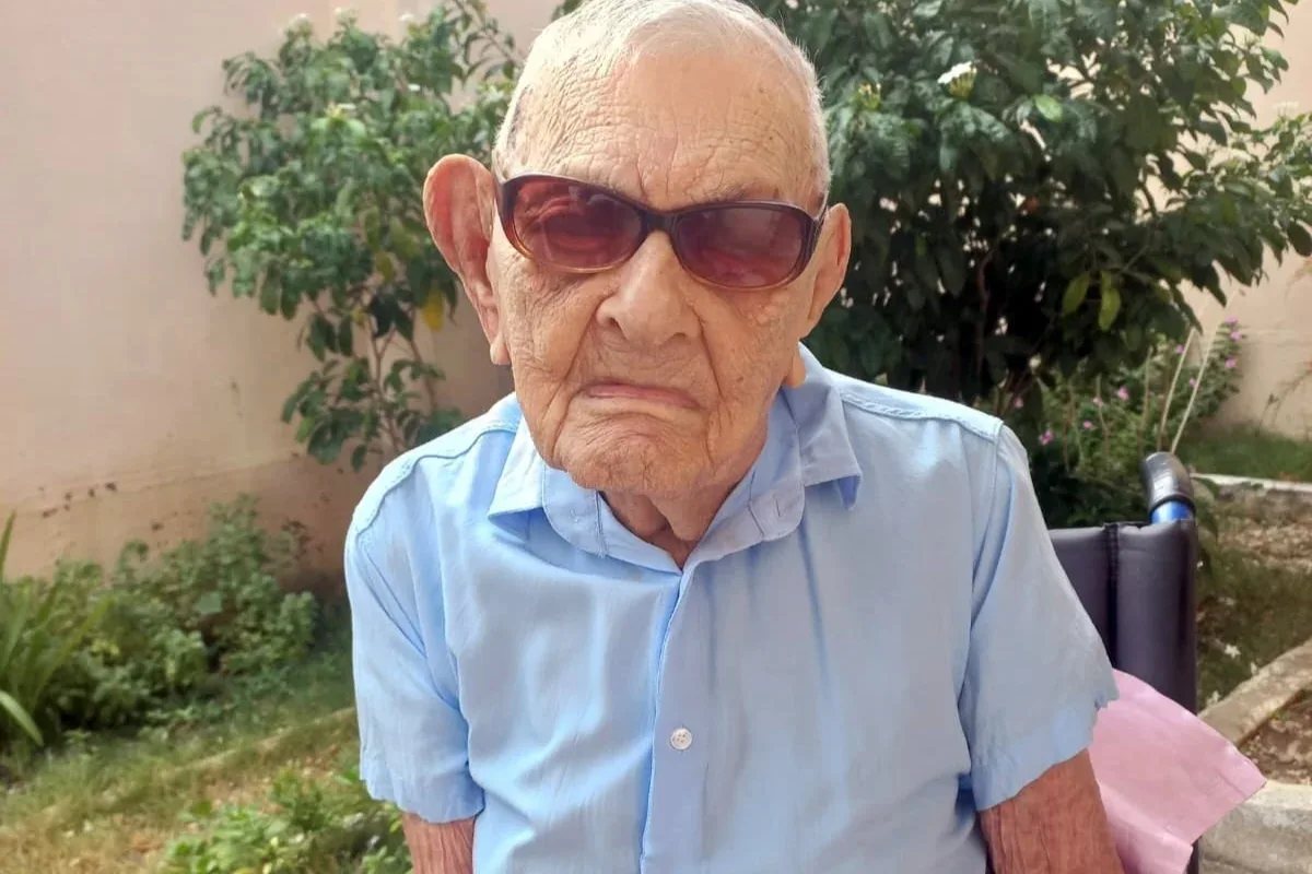 João Marinho Neto sentado em cadeira, cercado por familiares durante festa de 114 anos.