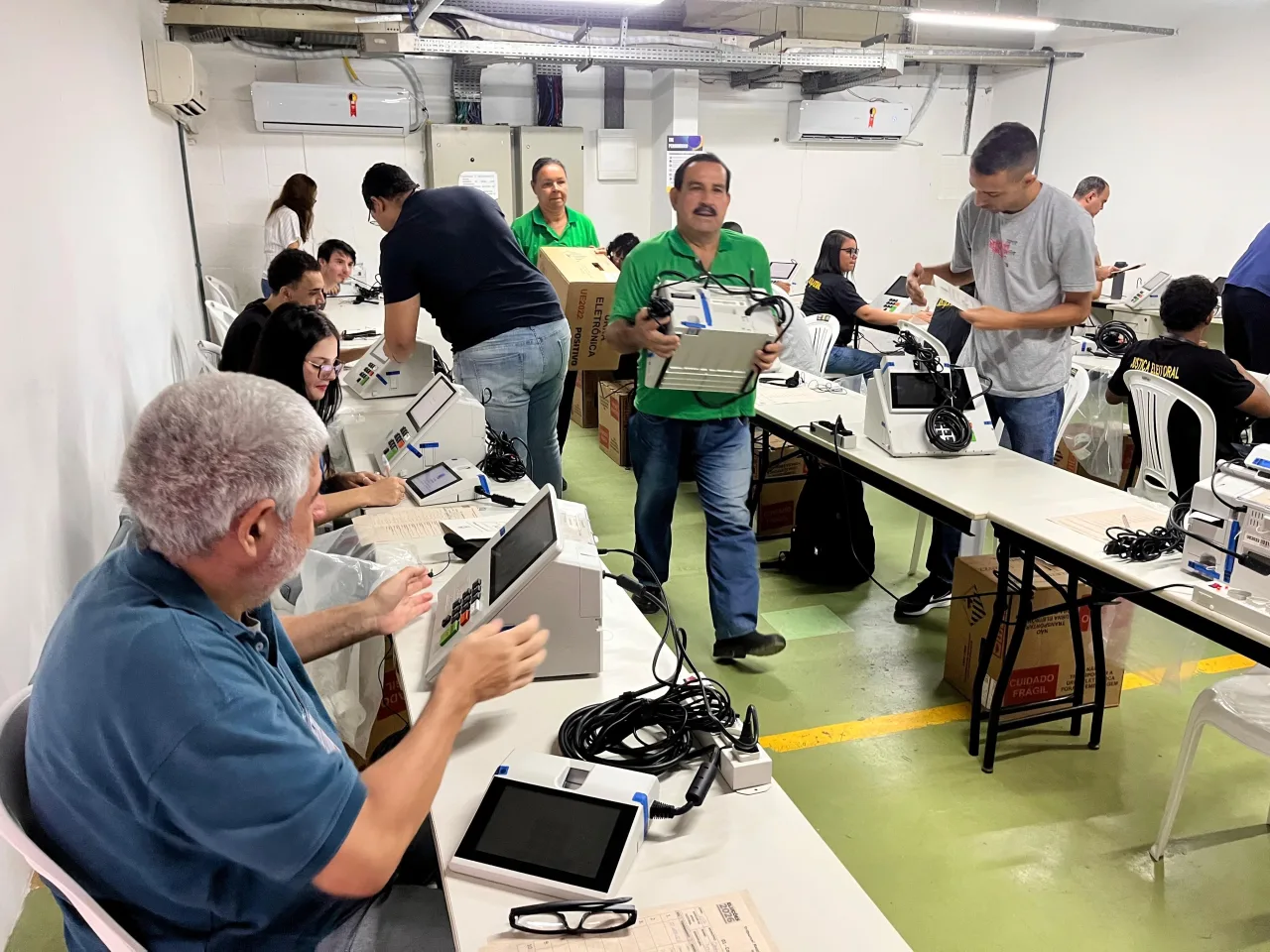 Urnas eletrônicas sendo organizadas em uma seção eleitoral